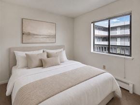 Anchorage apartment for rent - A bedroom with a large bed and a window overlooking a balcony.