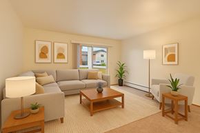 Anchorage apartment for rent - A living room with a grey couch, a wooden coffee table, a lamp, and two potted plants.