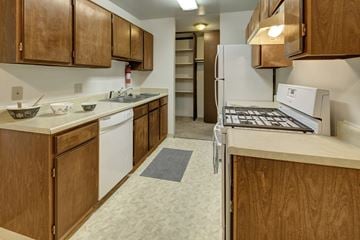 Anchorage apartment for rent - A kitchen with wooden cabinets and a white fridge.