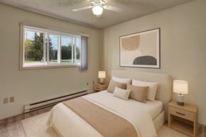 Anchorage apartment for rent - A bedroom with a large bed, a ceiling fan, and a window with a view of trees.