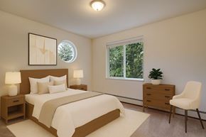 Anchorage apartment for rent - A cozy bedroom here at the Highlands Luxurywith a large, comfortable, and neutral-toned bed. Includes an accent chair in the corner, two nightstands between the bed with soft-toned lamps, a small wooden dresser with a simple plant, and a spacious window overlooking the forest trees. A small circular window sits atop the wall where the bed is placed.