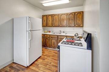 Anchorage apartment for rent - A kitchen with a white refrigerator and a white stove with a black pot on it.