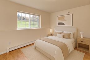 Eagle River apartment for rent - A bedroom with a large bed, nightstand, and window.