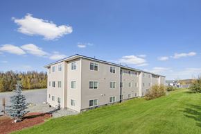 Eagle River apartment for rent - A large apartment building with a green lawn in front.