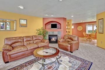 Anchorage apartment for rent - A living room with a brown leather couch and a fireplace.