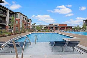 Rogers apartment for rent - A swimming pool with a slide and lounge chairs in front of apartment buildings.