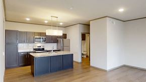 Rogers apartment for rent - A modern kitchen with dark grey cabinets and a white island.