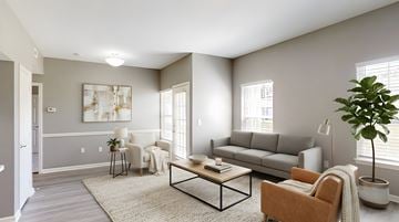 Bentonville apartment for rent - A living room with a grey couch, a coffee table, a potted plant, and a painting on the wall.