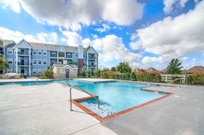 Bentonville apartment for rent - A large swimming pool in front of a multi-story apartment building.