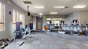 Phoenix apartment for rent - A bright community fitness center here at Arezzo featuring treadmills, ellipticals, strength training machines, mirrored walls, large windows for natural light, patterned flooring, and open workout space designed for residents to exercise comfortably and enjoy a well-equipped indoor gym.