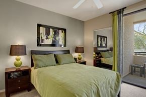 Phoenix apartment for rent - A bedroom with a bed, two lamps, and a painting on the wall.