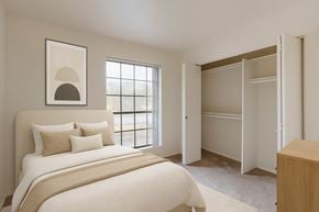 Phoenix apartment for rent - A serene bedroom here at Aspire Pinnacle Park featuring soft neutral walls, plush carpeting, and a large window that fills the space with natural light. The room includes a spacious walk-in closet with double doors and ample hanging storage, creating a bright and functional retreat with a calm, inviting atmosphere.