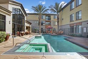 Phoenix apartment for rent - A vibrant and refreshing pool area here at Bolero featuring a sparkling swimming pool with a built-in spa and sleek tile detailing. Lounge chairs and shaded cabanas create inviting spaces to relax, while tall palm trees and surrounding architecture provide a private, resort-style atmosphere perfect for enjoying sunny days outdoors.