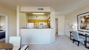 Chandler apartment for rent - A functional open-concept layout here at Dobson Towne Center featuring plush carpet and neutral walls that create a bright, airy feel. A breakfast bar connects the living area to a kitchen with warm wood cabinetry and white appliances, while a built-in desk nook adds convenient workspace within the home.