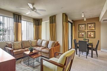 Peoria apartment for rent - A living room with a brown sofa, a coffee table, and a dining table with chairs.