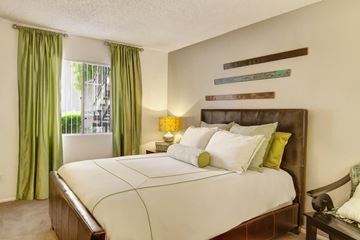 Phoenix apartment for rent - A bedroom with a large bed and green curtains.