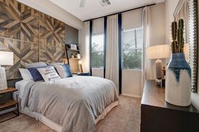 Phoenix apartment for rent - A bedroom with a large bed and a cactus on the side table.