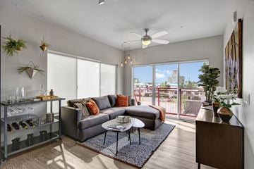 Phoenix apartment for rent - A living room with a grey couch and a glass table.