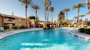 Glendale apartment for rent - A swimming pool surrounded by palm trees and buildings.