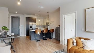 Phoenix apartment for rent - A modern living room with a brown leather couch and a kitchen area in the background.