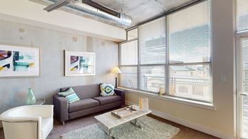 Phoenix apartment for rent - A living room with a grey couch, a white chair, a coffee table, and a painting on the wall.
