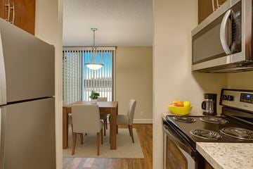 Calgary apartment for rent - A kitchen with a refrigerator, microwave, oven, and a dining table with chairs.
