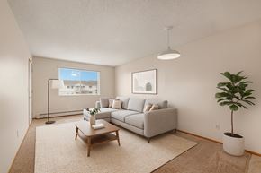 Camrose apartment for rent - A bright living room here at Aspen Terrace with beige carpeting, a light gray sectional sofa with neutral throw pillows, and a simple wooden coffee table on a textured cream area rug.