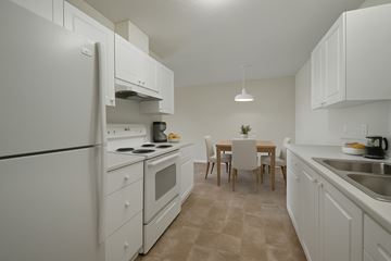 Camrose apartment for rent - A kitchen with white appliances and a table set for two.
