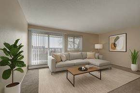 Edmonton apartment for rent - A bright living room here at Cedar Gardens featuring a spacious light gray sectional with neutral throw pillows, a warm wood coffee table, and a soft area rug, complemented by large windows, simple wall art, and lush greenery for a cozy, welcoming feel.