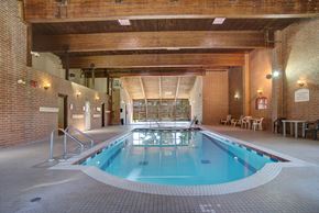 Saskatoon apartment for rent - Here at Edgemont Heights, enjoy a bright indoor pool area with sparkling blue water, classic brick walls, and warm wood-beam ceilings, plus plenty of deck space with seating for relaxing.