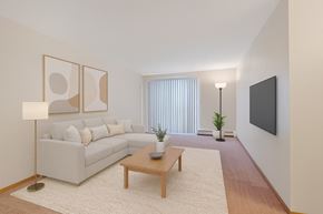 Leduc apartment for rent - A bright living room here at Edgewood Estates featuring a cozy light-gray sectional with neutral throw pillows, paired with a wooden coffee table on a soft area rug, plus modern wall art, warm floor lamps, and vertical blinds for a clean, inviting vibe.