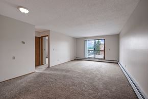 St. Albert apartment for rent - A bright living room here at Gateway Square featuring soft carpeting, crisp light walls, and a large sliding glass door that opens to a private balcony, filling the space with natural light and an airy feel.