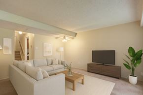 Edmonton apartment for rent - A bright, modern living room here at Lakewood Heights with a light gray sectional sofa, a wooden coffee table, neutral wall art, soft carpeted flooring, and a media console with a TV, creating a warm and inviting atmosphere.