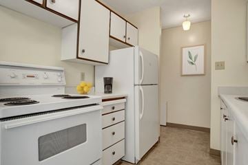 Saskatoon apartment for rent - A white stove and refrigerator in a kitchen with a painting hanging on the wall.
