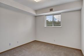 Winnipeg apartment for rent - A bright, empty bedroom here at Quail Ridge with soft carpet, clean white walls, and a wide window with blinds letting in natural light. A recessed ceiling detail adds a cozy touch while keeping the space open and versatile.