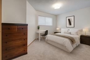 Fort St. John apartment for rent - A bedroom with a bed, desk, chair, and dresser.