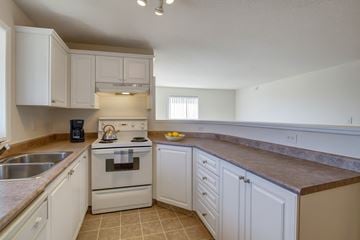 Calgary apartment for rent - A kitchen with white cabinets and a stove top oven.