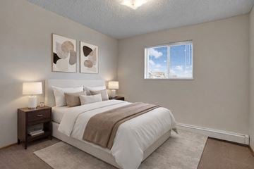 Saskatoon apartment for rent - A bedroom with a large bed and two wall lamps.