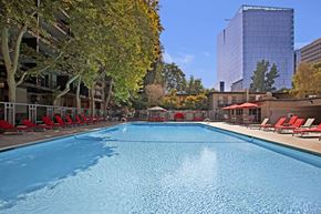 Sacramento apartment for rent - A large blue swimming pool surrounded by trees and chairs.
