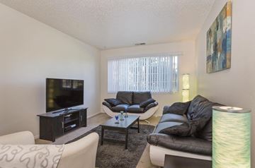 Colorado Springs apartment for rent - A living room with a black leather couch and a television.