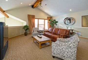 Colorado Springs apartment for rent - A living room with a brown leather couch and a patterned armchair.