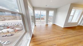 Colorado Springs apartment for rent - A bright open living and dining area here at Experience at Epicenter featuring wide wood-style flooring, an accent wall, and expansive windows with simple shades that overlook the surrounding neighborhood. A modern pendant light defines the dining space, while the open layout and natural light create a spacious, airy setting ideal for relaxing or entertaining.