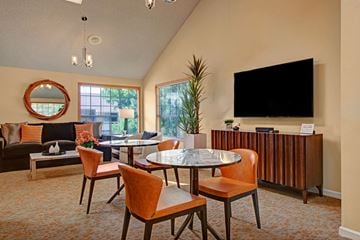 Colorado Springs apartment for rent - A living room with a round mirror, a fireplace, a dining table with chairs, and a television.