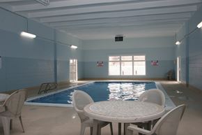 Colorado Springs apartment for rent - A spacious indoor pool area here at Hyde Park North Apartments with a rectangular swimming pool surrounded by a concrete deck. Natural light enters through large windows, while poolside tables and chairs offer space to relax. Light blue walls, overhead lighting, and easy pool access create a comfortable, year-round amenity.