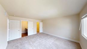 Colorado Springs apartment for rent - A spacious neutral bedroom here at Retreat at Austin Bluffs featuring soft carpet flooring, light-toned walls, and a wide layout with ample room for furnishings. Double doors open to an adjacent bathroom and walk-in closet, while a large window brings in natural light and creates a bright, comfortable atmosphere.