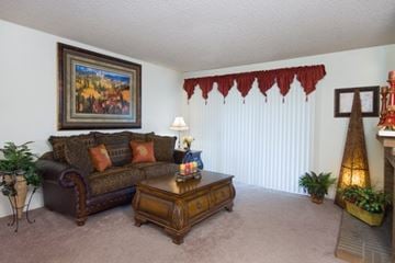 Colorado Springs apartment for rent - A living room with a brown couch, a coffee table, and a painting on the wall.