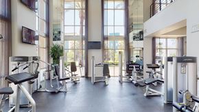 Corona apartment for rent - A bright fitness center here at Artisan at Main Street Metro featuring floor-to-ceiling windows that fill the space with natural light, modern cardio and strength training equipment arranged on dark flooring, mounted televisions, tall mirrors, and high ceilings that create an open, energizing workout environment.