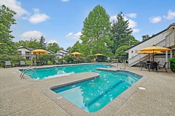 Outdoor pool with lounge chairs and tables with umbrellas