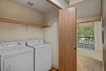 Hall closet with full size washer and dryer with shelving