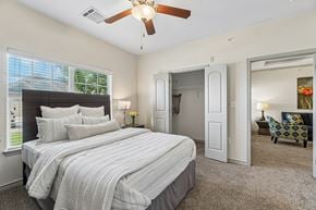Oklahoma City apartment for rent - A bedroom with a large bed and a ceiling fan.